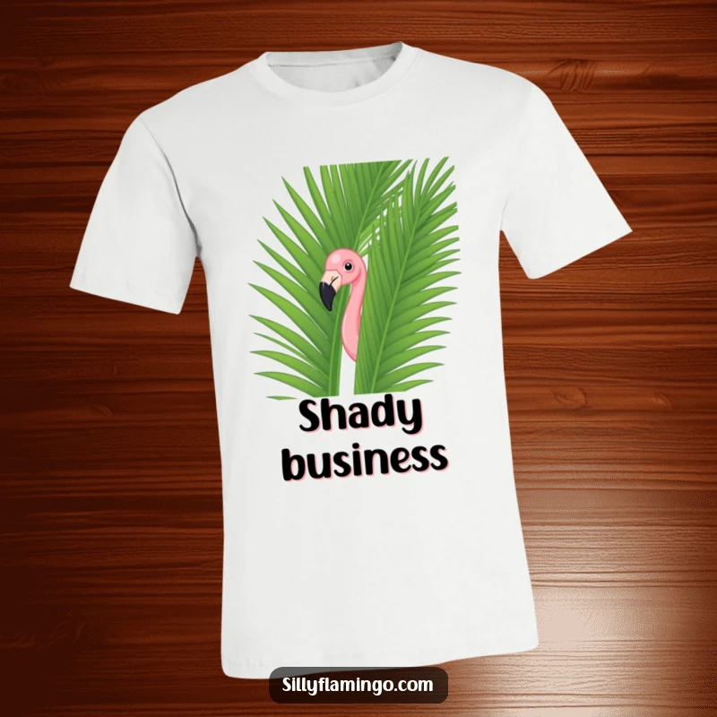 Funny flamingo caught in a comical peek-a-boo behind a large green palm leaf on a comfortable t-shirt.